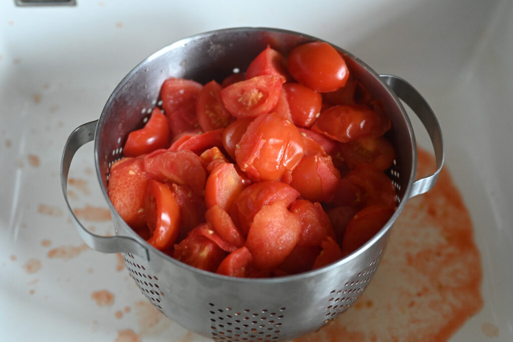 Die gekochten Tomaten in ein großes Abropfsieb geben und abtropfen lassen